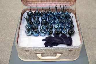 Yhonnie Scarce, Andomooka opal fields, South Australia (Detail), 2018, from the serier Remember Royaltu, 2018, Water based ink screen printed on vintage cotton sheet, vintage suitcase, black blown glass, vintage gloves, embroidered handkerchiefs, sheet: 260 x 230 cm, suitcase with objects 62 x 47 x 50 cm, Installation view, Australian Centre for Contemporary Art (ACCA), 2018, Photo Andrew Curtis, Courtesy the artist and This is No Fantasy + Dianne Tanzer Gallery Melbourne