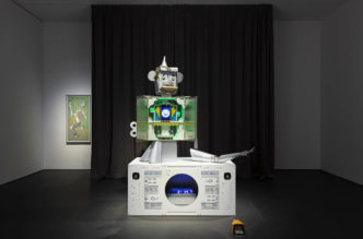 Simon Fujiwara, Who‘s Only Whoman?, 2021, Sculpture: wood, cardboard, paper, adhesive tape, gears, motors, magnets, cabling, metal, Plexiglas, ready-made, pedal switch, Plinth: wood, Plexiglas, speakers, amplifier, media player, servo box, wiring, lock, switch, Duration of song: 1:16 min., 235 x 162 x 75 cm (sculpture), 12,5 x 14,5 x 27 cm (pedal switch), © Simon Fujiwara, Courtesy the artist and Esther Schipper Gallery