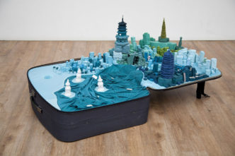 Yin Xiuzhen, Portable City: Hangzhou, 2011, suitcase, clothes, magnifying glass, map, sound element11" x 59-13/16" x 34-5/8" (28 cm x 152 cm x 88 cm), © Yin Xiuzhen, Courtesy the artist and Pace Gallery